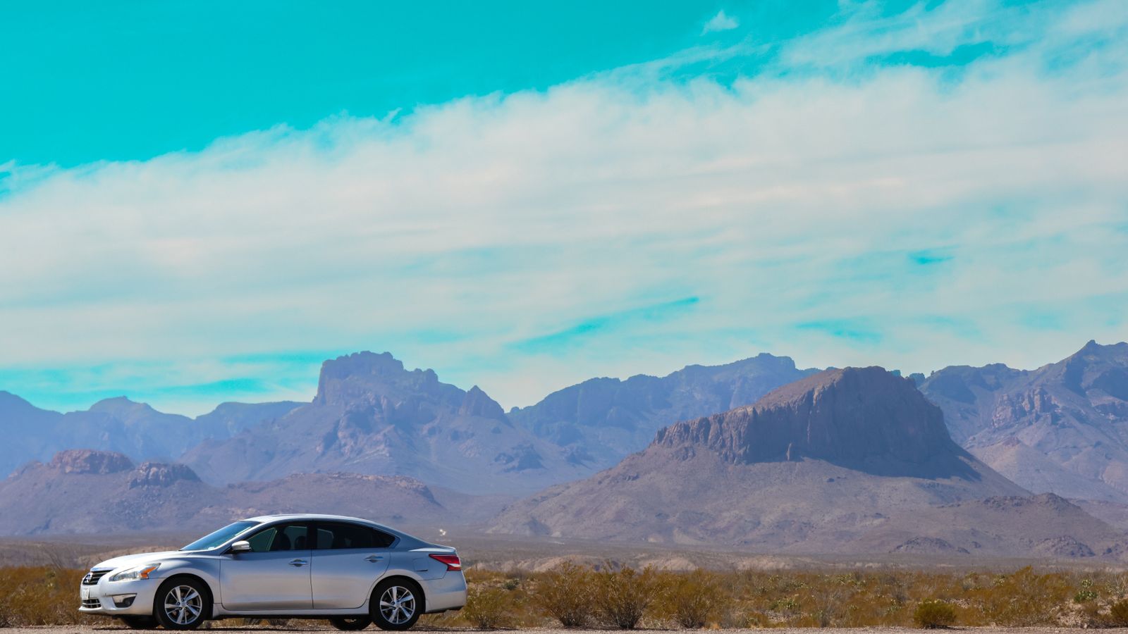 Car on a desert highway with mountains ahead