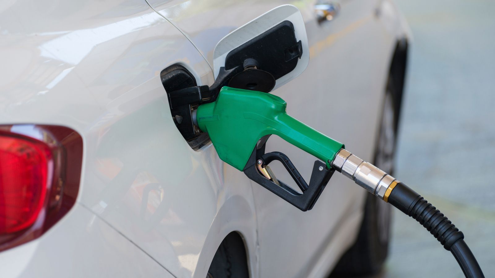 Green fuel nozzle filling a white car