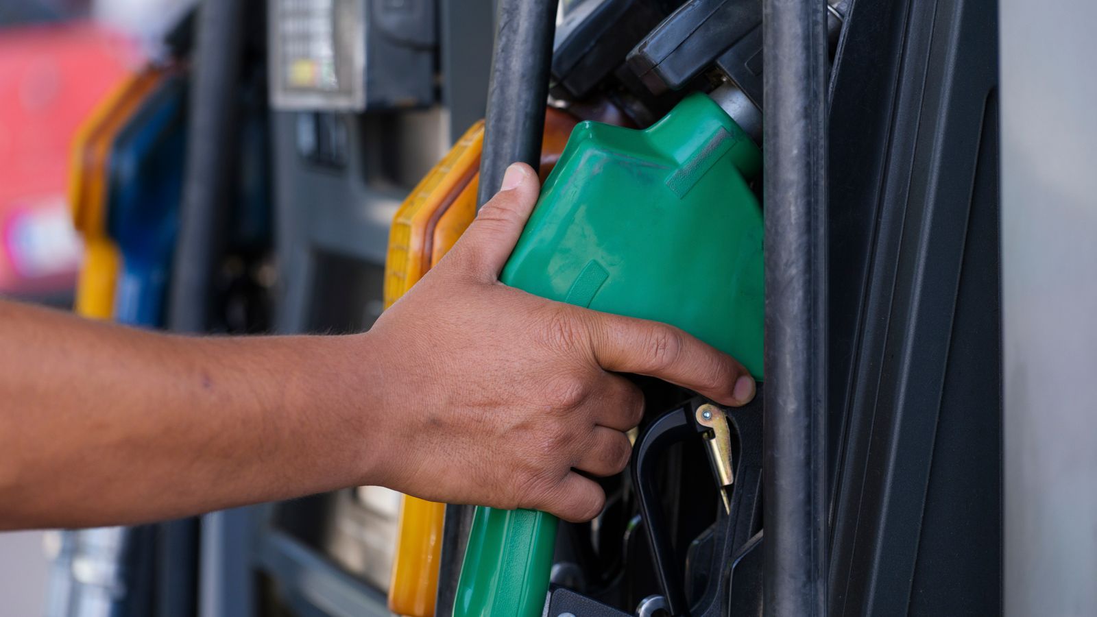 Hand holding a gas pump nozzle