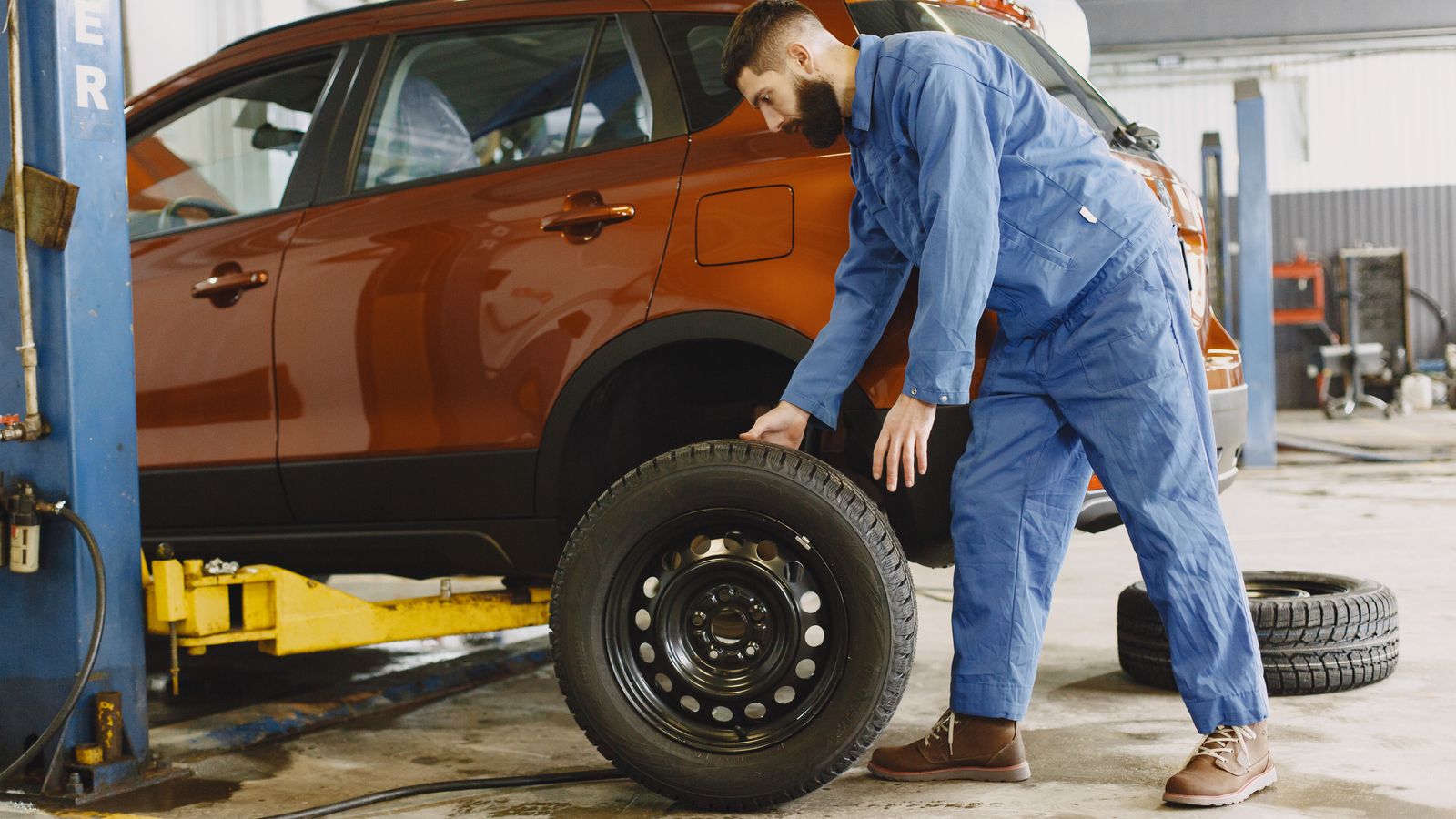 Mechanic fitting a tire on an SUV in a service bay